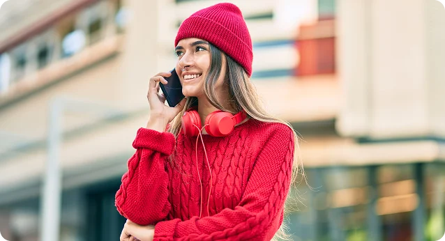 Woman in a red sweater holding a phone outdoors